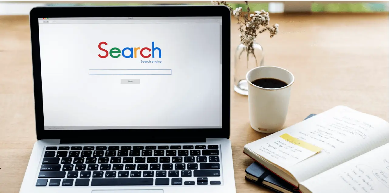 ノート、コーヒー、そして検索ページが表示されたラップトップは、Google AIの概要とコンテンツリサーチを象徴しています。